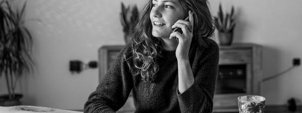 imagen en blanco y negro de una mujer sentada en una mesa hablando por teléfono