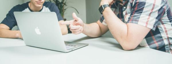 Dos personas delante de un ordenador hablanso sobre algo en lo que están trabajando