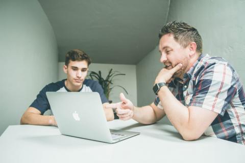 Dos personas delante de un ordenador hablanso sobre algo en lo que están trabajando